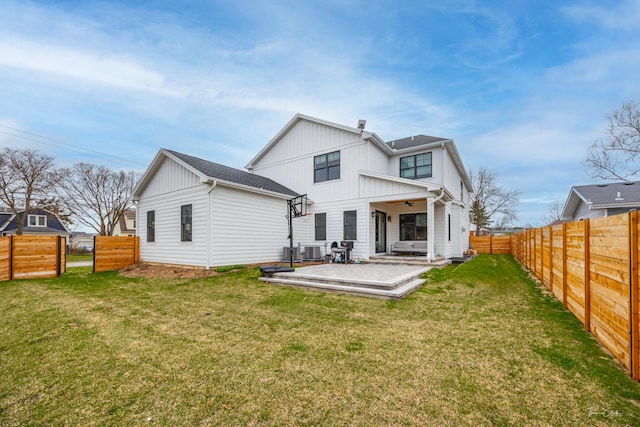 rear view of house featuring board and batten siding, ceiling fan, a fenced backyard, a yard, and a patio