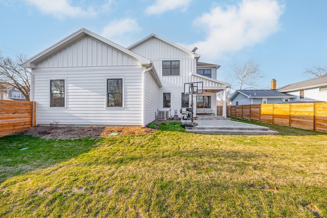 back of property with a fenced backyard, a patio, board and batten siding, and a yard