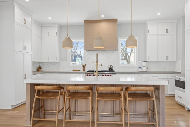 kitchen featuring backsplash, light wood-style flooring, and white cabinetry