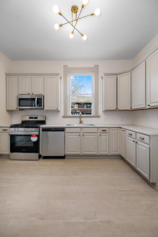 505 S Indiana Ave, Kankakee, IL 60901 - kitchen featuring decorative backsplash, a sink, a notable chandelier, and stainless steel appliances