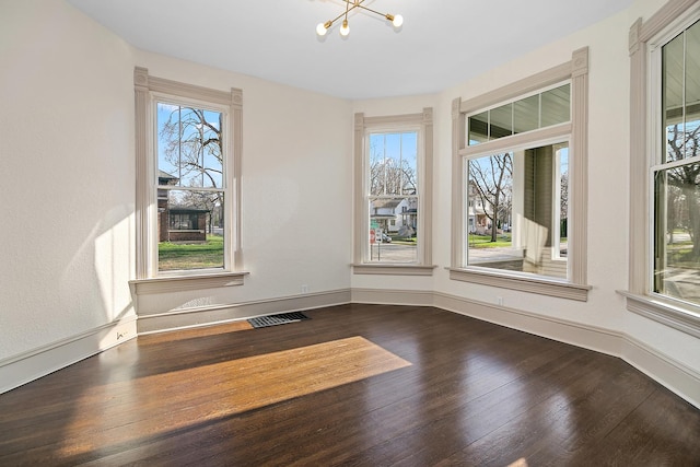 505 S Indiana Ave, Kankakee, IL 60901 - unfurnished room featuring a wealth of natural light, visible vents, dark wood-style flooring, and an inviting chandelier