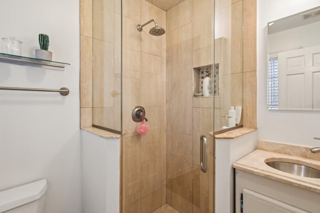 bathroom featuring toilet, visible vents, a shower stall, and vanity