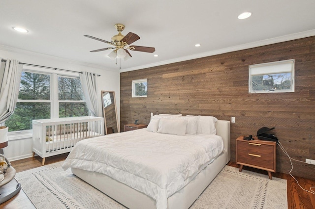 bedroom with wood walls, ornamental molding, wood finished floors, ceiling fan, and recessed lighting