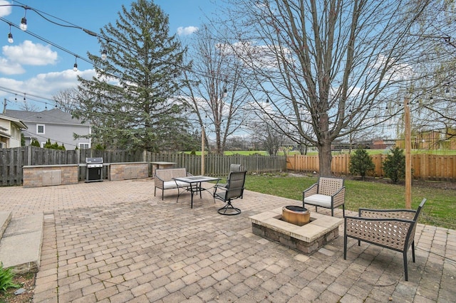 view of patio featuring a fenced backyard, an outdoor fire pit, exterior kitchen, and grilling area