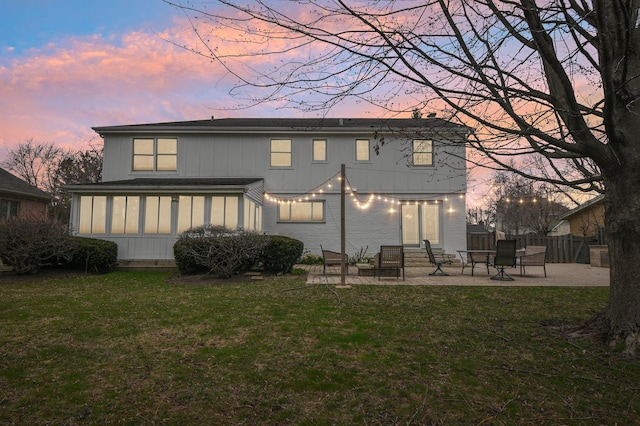 back of property at dusk featuring a yard, entry steps, fence, and a patio area