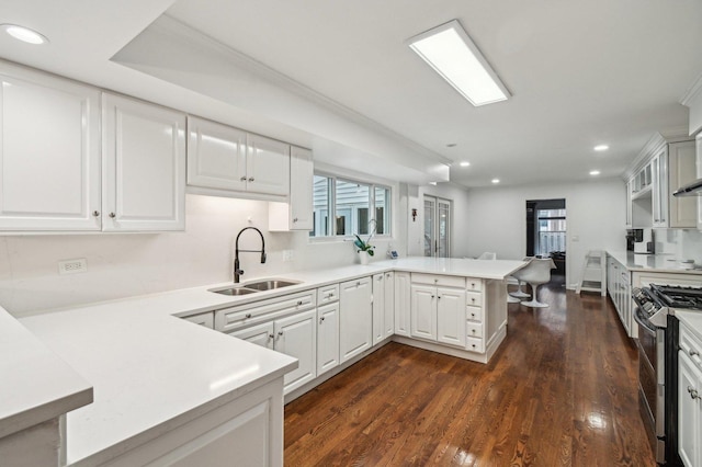 kitchen with a peninsula, recessed lighting, light countertops, a sink, and double oven range