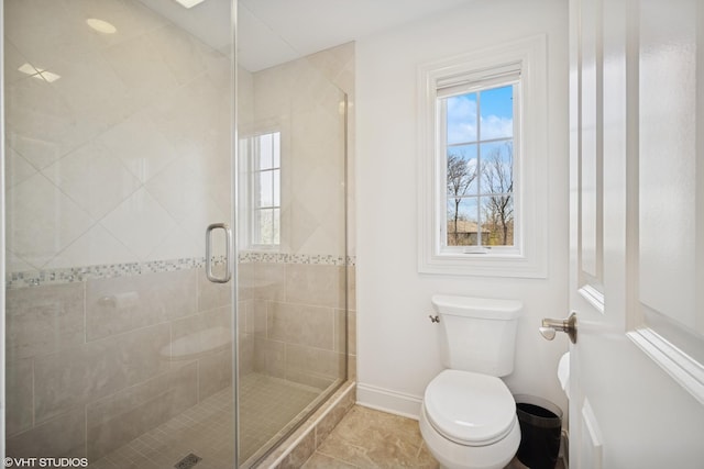 bathroom with toilet, a shower stall, and baseboards