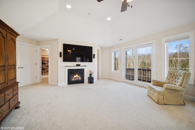 living room with light carpet, ceiling fan, baseboards, and vaulted ceiling
