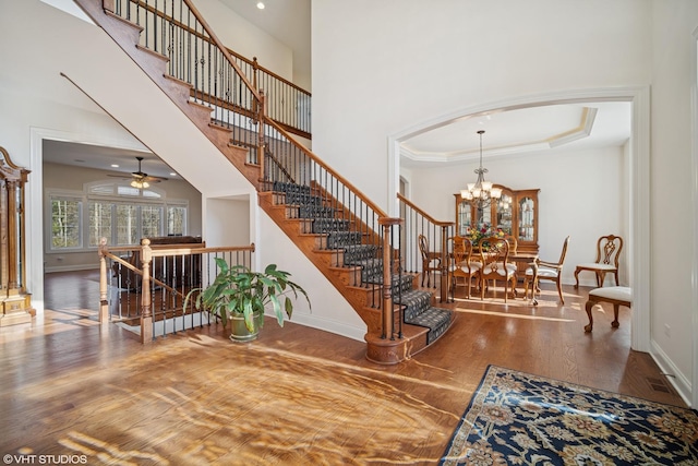 stairway featuring baseboards, arched walkways, a high ceiling, and wood finished floors