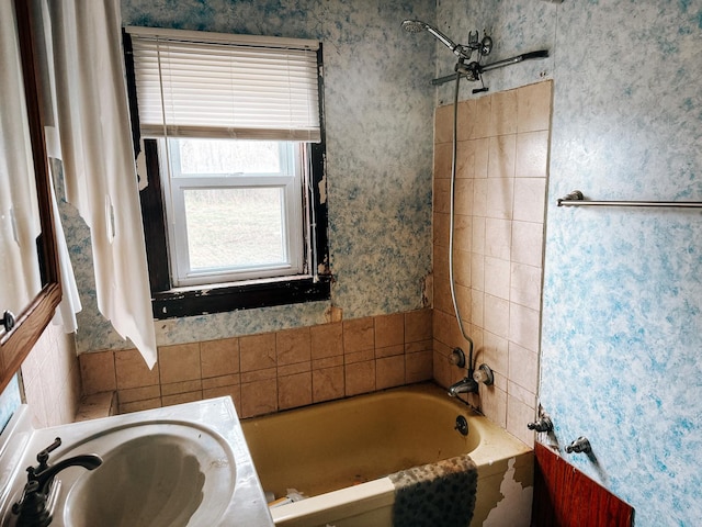 full bath featuring a shower, wallpapered walls, a sink, and a bathtub