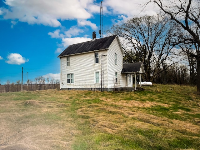 view of side of property with a chimney and a lawn