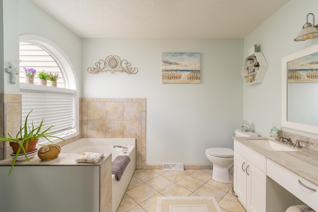 full bathroom featuring a textured ceiling, a garden tub, vanity, toilet, and tile patterned flooring
