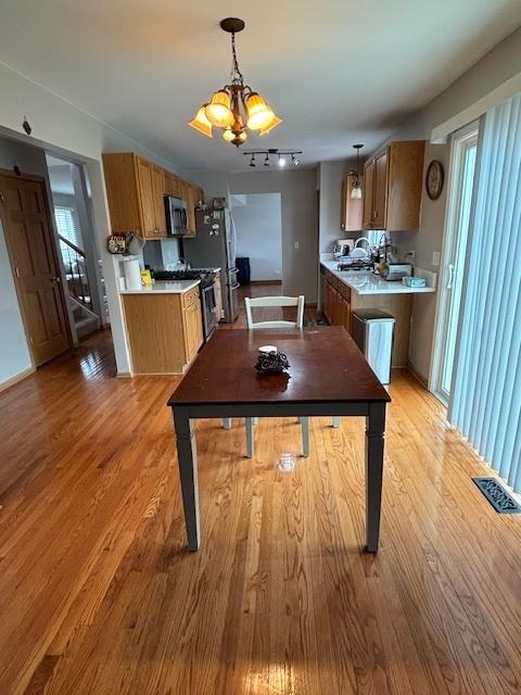 678 Meridian Way, Antioch, IL 60002 - kitchen featuring light wood-style flooring, appliances with stainless steel finishes, light countertops, brown cabinets, and a notable chandelier