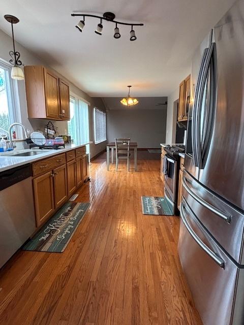 678 Meridian Way, Antioch, IL 60002 - kitchen featuring light wood-style floors, a sink, stainless steel appliances, decorative light fixtures, and brown cabinets