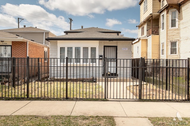 view of front of property featuring roof with shingles, a fenced front yard, and a gate