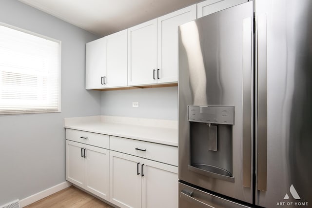 kitchen featuring baseboards, light countertops, white cabinetry, stainless steel refrigerator with ice dispenser, and visible vents