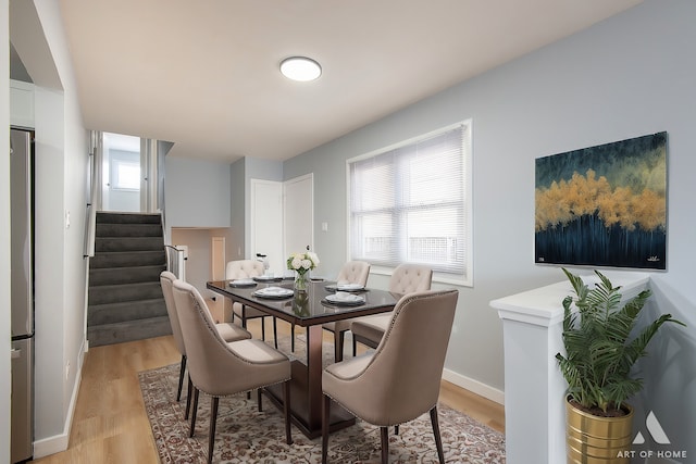 dining room with stairway, light wood-type flooring, and baseboards