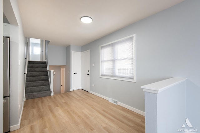 interior space with visible vents, baseboards, light wood finished floors, and stairs