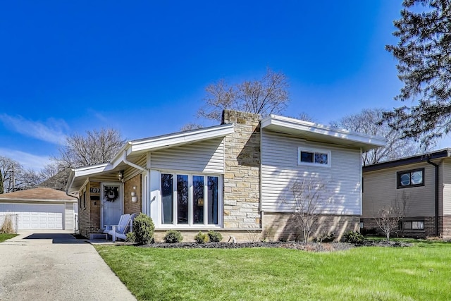 view of front of property with a front yard, a detached garage, an outdoor structure, and stone siding