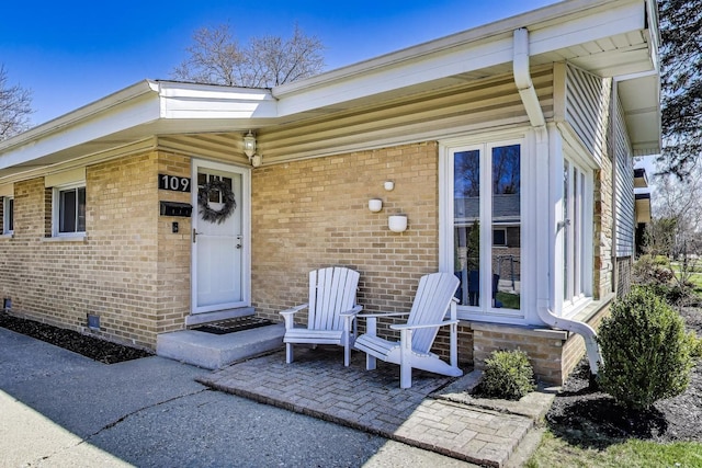 entrance to property featuring a patio area and brick siding