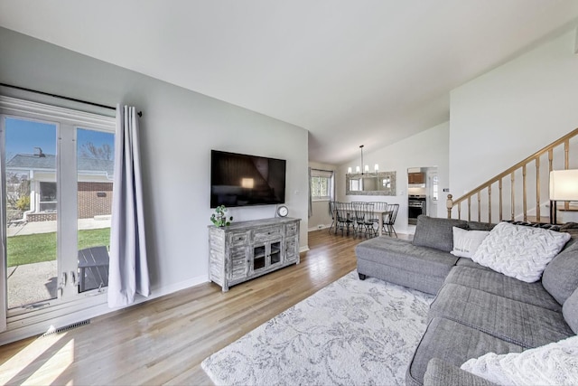 living area with a chandelier, stairway, visible vents, lofted ceiling, and wood finished floors