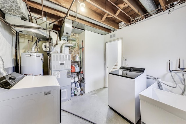 clothes washing area featuring water heater, washer and clothes dryer, and a sink