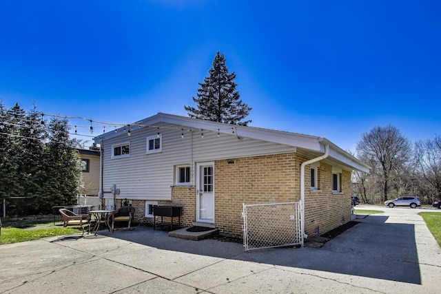 rear view of property featuring brick siding and a patio area
