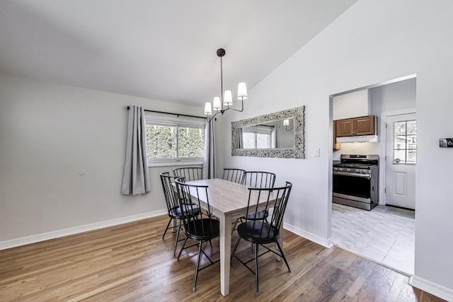 dining area with a chandelier, high vaulted ceiling, light wood-type flooring, and baseboards