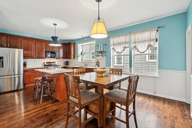 dining room featuring a wainscoted wall and dark wood finished floors