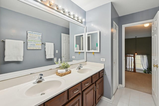 full bath with tile patterned floors, double vanity, baseboards, and a sink