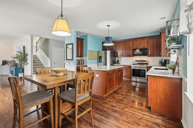 kitchen featuring a kitchen island, appliances with stainless steel finishes, a sink, decorative backsplash, and dark wood-style floors