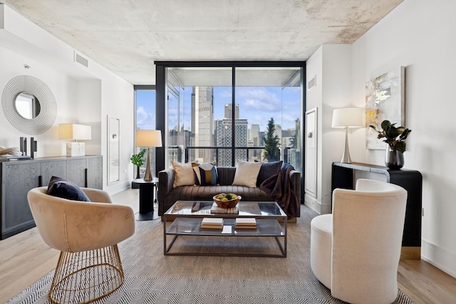 living room with visible vents, a wall of windows, wood finished floors, and baseboards
