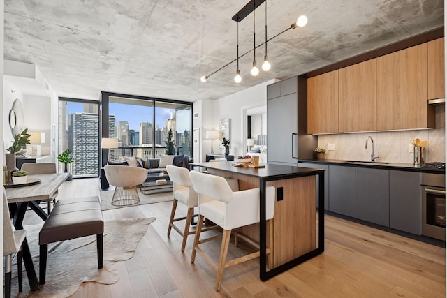 kitchen featuring modern cabinets, a sink, dark countertops, light wood-type flooring, and wall oven