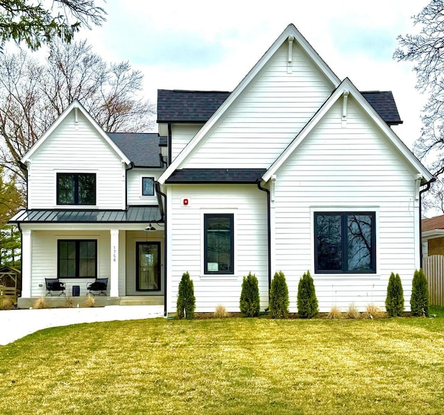 view of front facade featuring a shingled roof, a porch, and a front lawn