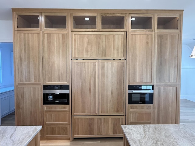 kitchen with glass insert cabinets, oven, and light stone counters