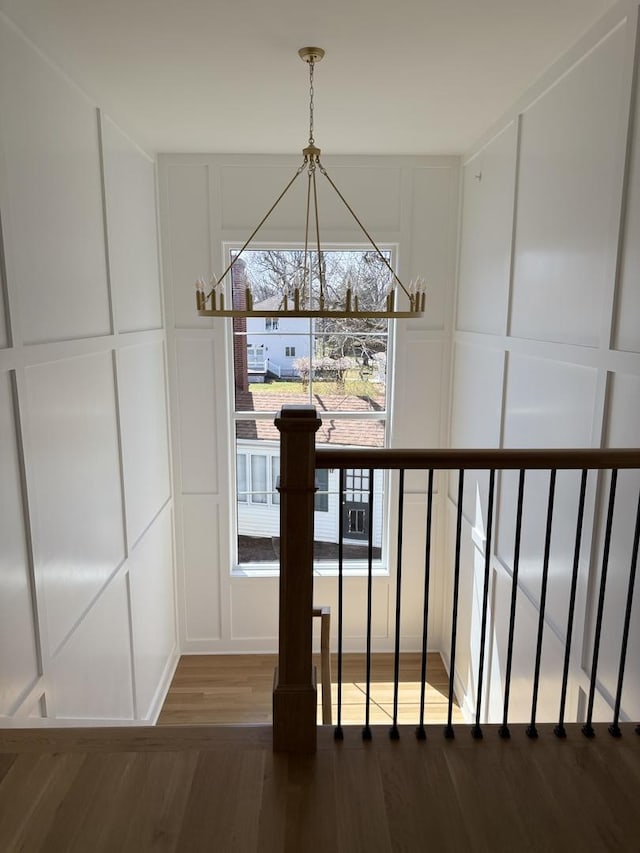 interior space featuring a decorative wall, a notable chandelier, and wood finished floors