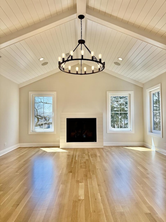 unfurnished living room with light wood finished floors, a notable chandelier, and a healthy amount of sunlight