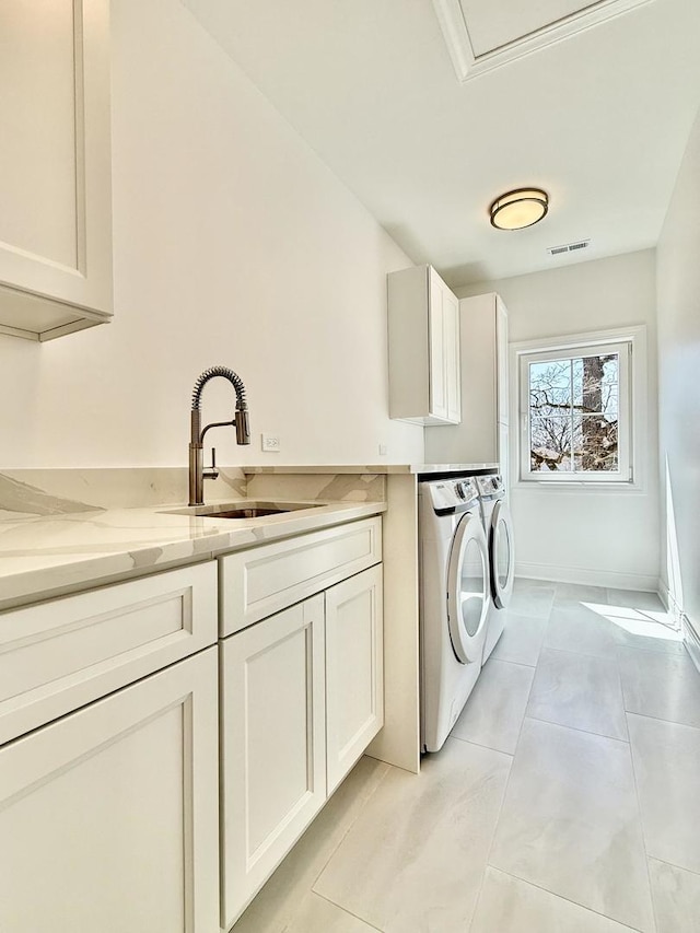 washroom with washing machine and clothes dryer, light tile patterned flooring, visible vents, cabinet space, and a sink