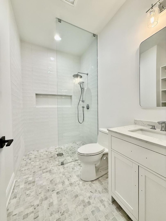 full bathroom featuring toilet, tiled shower, and vanity