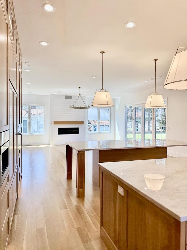 kitchen featuring recessed lighting, light wood-style floors, a spacious island, and a fireplace