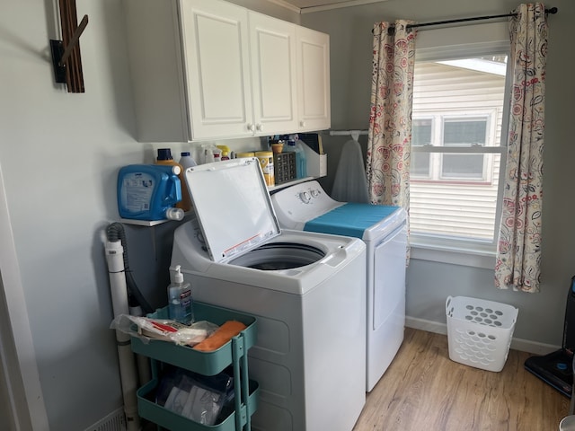 laundry area featuring washing machine and dryer, light wood-style flooring, baseboards, and cabinet space