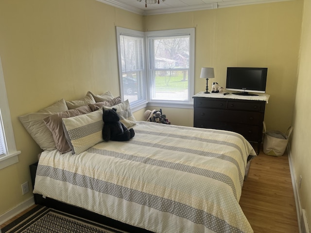 bedroom with baseboards, wood finished floors, and ornamental molding