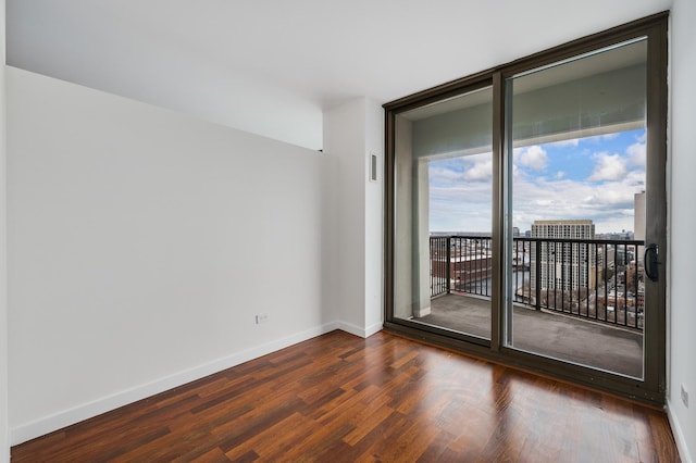 spare room with visible vents, floor to ceiling windows, dark wood finished floors, and baseboards