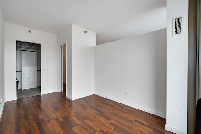 unfurnished bedroom with a closet, visible vents, baseboards, and wood finished floors