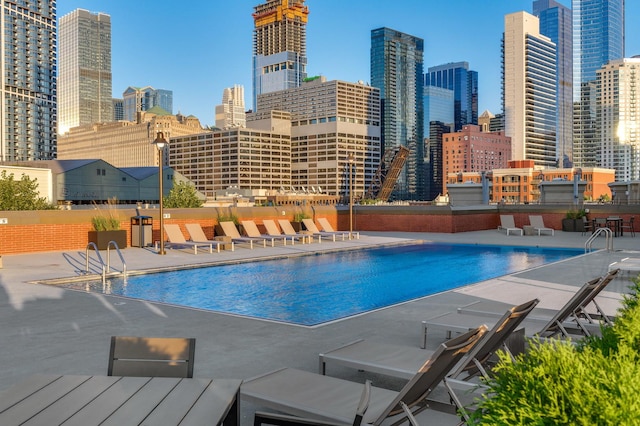community pool with a patio area and a city view