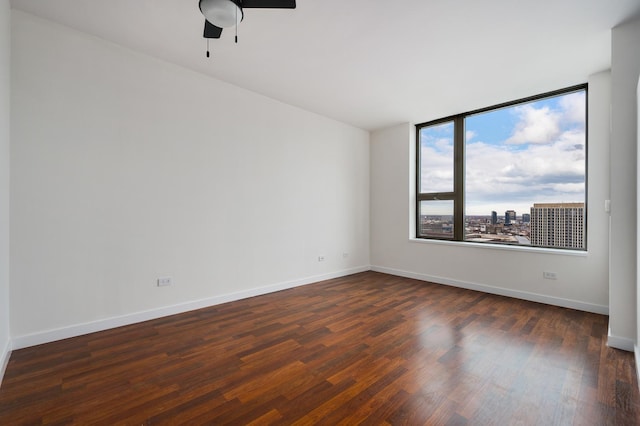 spare room with dark wood-type flooring, baseboards, and ceiling fan