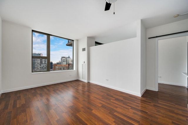 unfurnished room with a barn door, ceiling fan, baseboards, and wood finished floors