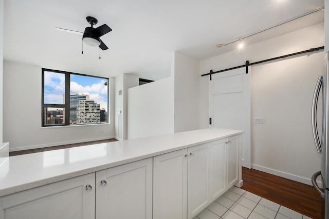 interior space featuring track lighting, freestanding refrigerator, white cabinets, a barn door, and ceiling fan