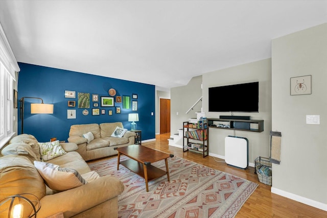 living area with stairs, wood finished floors, and baseboards