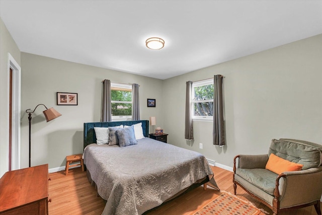 bedroom with multiple windows, light wood-type flooring, and baseboards